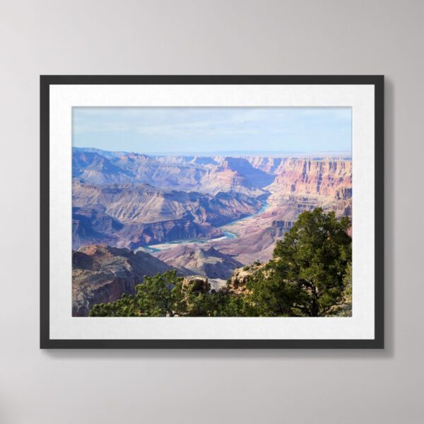 A stunning view of the Colorado River winding through the Grand Canyon, with rugged canyon walls, vibrant greenery, and expansive desert landscapes under a clear blue sky.