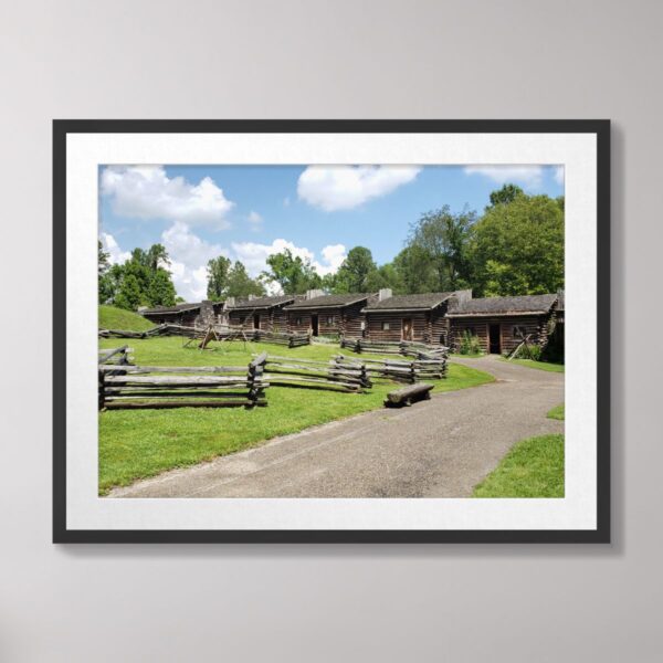 Photograph of Daniel Boone's Fort Boonesborough in Kentucky, featuring rustic log cabins, split-rail fences, and a lush green landscape.