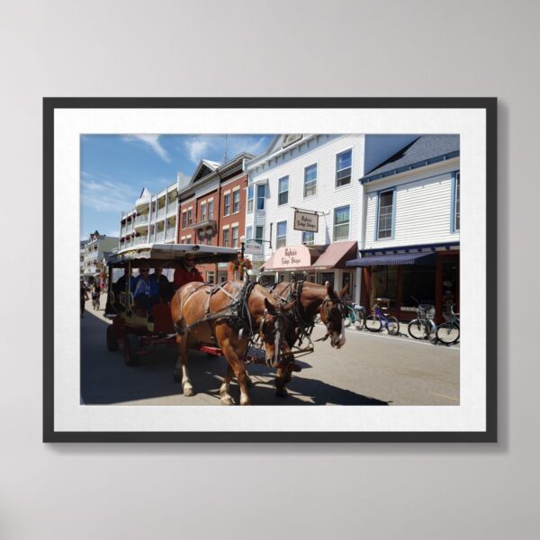 Horse-drawn carriage in downtown Mackinac Island, Michigan, surrounded by charming storefronts and a motor-free street scene.