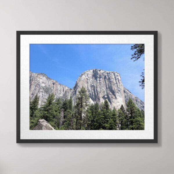 A stunning view of El Capitan, a granite monolith in Yosemite National Park, surrounded by a lush forest and under a bright blue sky.