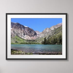 A scenic view of Parker Lake in the Ansel Adams Wilderness near June Lake, California, surrounded by lush greenery, tall trees, and the majestic Sierra Nevada mountains under a vibrant blue sky.