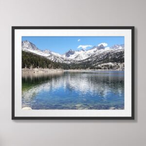 A scenic view of South Lake in Bishop, California, featuring crystal-clear waters, snow-capped Sierra Nevada mountains, and lush green forests under a vibrant blue sky.