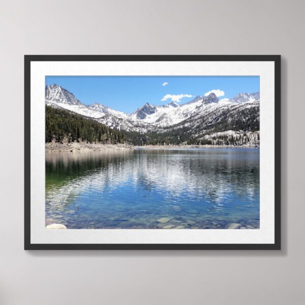 A scenic view of South Lake in Bishop, California, featuring crystal-clear waters, snow-capped Sierra Nevada mountains, and lush green forests under a vibrant blue sky.