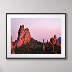 A stunning sunset photograph of the red rock formations at Garden of the Gods in Colorado Springs, Colorado, set against a pink and purple sky.