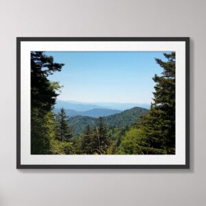 A scenic view of the Blue Ridge Mountains in North Carolina, showcasing layered green hills, dense forests, and a bright blue sky.