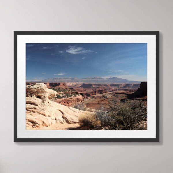 A stunning view of Canyonlands National Park in Moab, Utah, showcasing dramatic red-rock canyons and desert terrain under a vibrant blue sky.