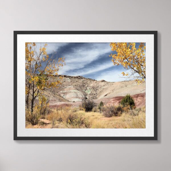 Colorful desert landscape in Moab, Utah, with vibrant hills, autumn foliage, and a dramatic sky.