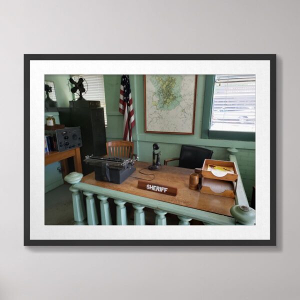 Photograph of a vintage sheriff’s office inspired by Andy Griffith’s Mayberry, featuring a typewriter, microphone, American flag, and map, taken in Mount Airy, North Carolina.