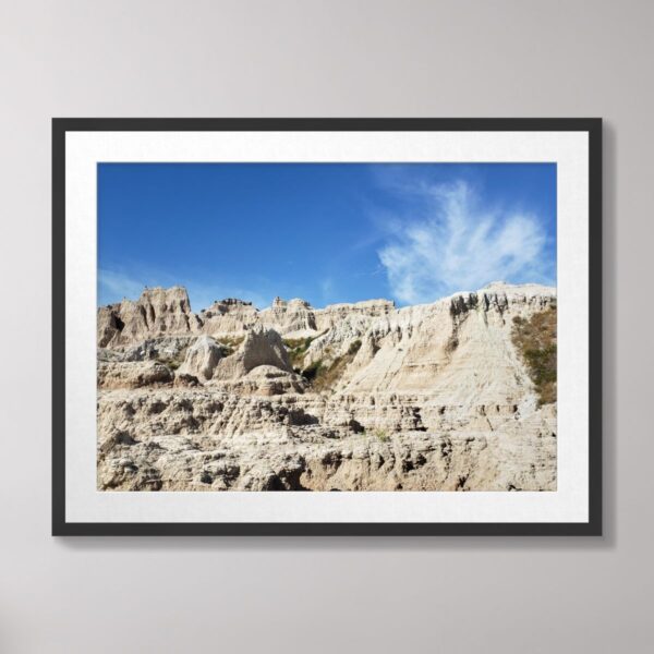 Photograph of rugged peaks and cliffs at Badlands National Park, South Dakota, with a vibrant blue sky.