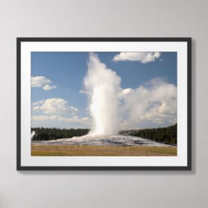 Old Faithful Geyser erupting at Yellowstone National Park under a clear blue sky.