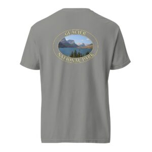 Grey Comfort Colors 1717 heavyweight T-shirt featuring Saint Mary Lake at Glacier National Park graphic with mountain peaks, evergreen trees, and blue waters in an oval design.