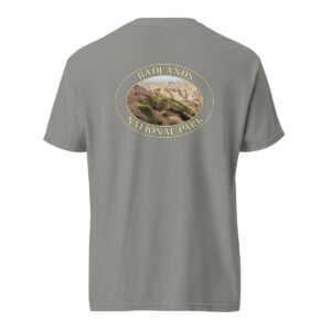 Grey Comfort Colors 1717 heavyweight T-shirt featuring a scenic graphic of Big Horn Sheep at Badlands National Park, framed in an oval design.