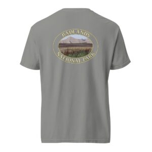 Grey Comfort Colors 1717 heavyweight T-shirt featuring a scenic graphic of reeds at Badlands National Park, framed in an oval design.