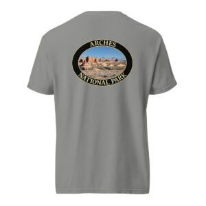 Grey Comfort Colors heavyweight T-shirt featuring a scenic view of The Windows at Arches National Park, framed in an oval border.