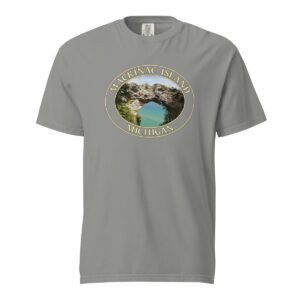 Grey Comfort Colors 1717 heavyweight T-shirt featuring Arch Rock on Mackinac Island, Michigan, with a scenic lake view framed by natural rock formations in an oval design.