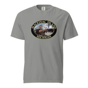 Grey Comfort Colors 1717 heavyweight T-shirt featuring downtown Mackinac Island horse and carriage graphic with historic buildings in an oval design.