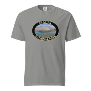 Grey Comfort Colors 1717 heavyweight T-shirt featuring Lake McDonald at Glacier National Park graphic with mountains and water reflection in an oval design.