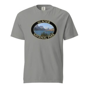 Grey Comfort Colors 1717 heavyweight T-shirt featuring Saint Mary Lake at Glacier National Park graphic with mountain peaks, evergreen trees, and blue waters in an oval design.