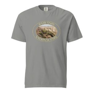 Grey Comfort Colors 1717 heavyweight T-shirt featuring a scenic graphic of Big Horn Sheep at Badlands National Park, framed in an oval design.