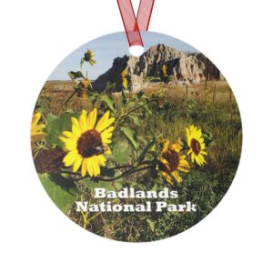 Badlands National Park ornament featuring a vibrant sunflower field with rugged terrain, 3.5-inch aluminum design with red ribbon.